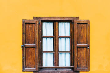 Wooden vintage window on yellow house wall background.
