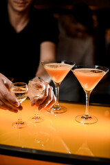 view of glasses with vodka which male hands holds on a bar counter