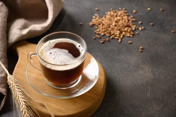 Foto op Plexiglas Koffiebar Barley coffee in glass cup, beans and ears of barley on brown background. Natural caffeine free organic coffee alternative. Beverage made of healthy blend of roasted barley. Close up. Copy space.