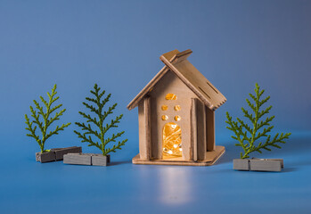 small homemade wooden house with a garland inside and a Christmas tree