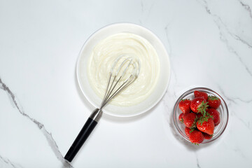 whipped cream and whisk on white background