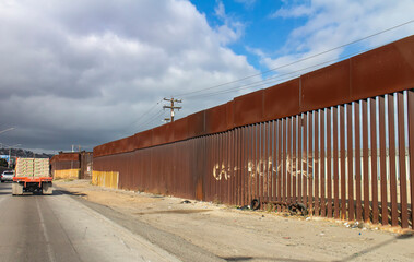 Fototapeta na wymiar View of border wall with as seen driving on road with truck in the distance