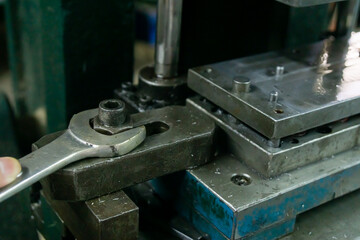 close up of a wrench, bolt and press stamping mold in factory