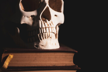 Human skull on vinatge books isolated on black background.