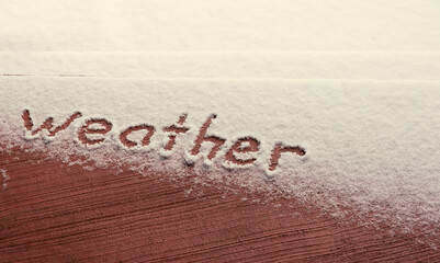 Hand written word weather in light snowfall. There is room for text message. Fresh white snow fell on  steps. Underneath color is color of cement. 