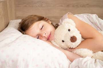 cute little girl sleeps in bed. dream girl hugging a plush toy.