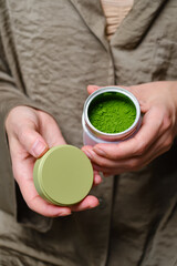 Matcha green tea powder in a jar in the hands of a girl. Organic Green Matcha Tea ceremony. Cooking with matcha, recipe
