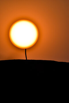 The sun balances on the pin