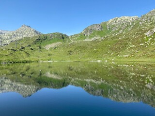 Naklejka na ściany i meble Summer atmosphere on the Lago di Rodont lake (Lake Rodont) in the Swiss alpine area of the mountain St. Gotthard Pass (Gotthardpass), Airolo - Canton of Ticino (Tessin), Switzerland (Schweiz)