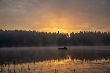 A man on a boat on a foggy lake