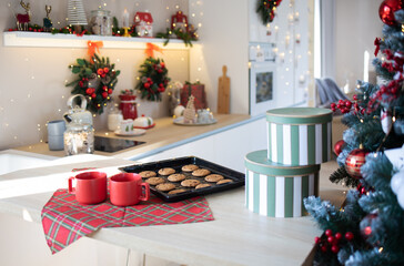 Red mugs with gingerbread cookies in the kitchen Christmas tree. December 25th. Christmas background. Concept; Noel, Merry Christmas, New Year holidays, holidays and weekends