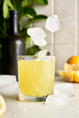Ice falling on a traditional italian homemade lemon alcohol drink liqueur limoncello 