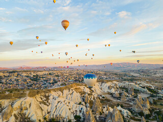 Breathtaking drone view of hundreds of hot air balloons ride over Turkey's iconic Cappadocia, the underground cities and fairy chimneys valley, rock formations, during the sunrise. High quality photo