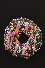 donut in dark chocolate glaze close-up on a black background, low key