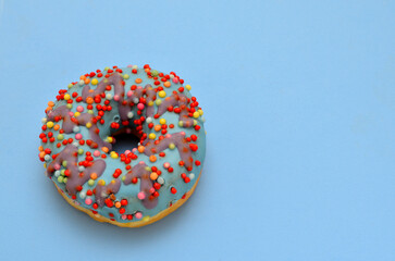 colorful donut with icing on on a blue background, copy space