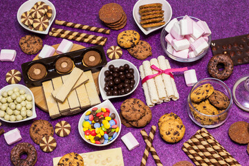 Chocolate and biscuits background. Chocolate and biscuits background. Many pieces of chocolate, candies, cookies, biscuits, cakes, donuts, and other sweets. Milk chocolate and dark chocolate, waffle c
