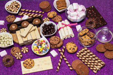 Naklejka na ściany i meble Chocolate and biscuits background. Chocolate and biscuits background. Many pieces of chocolate, candies, cookies, biscuits, cakes, donuts, and other sweets. Milk chocolate and dark chocolate, waffle c