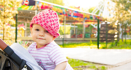 baby in a stroller in a green summer park. smiling baby in a hat