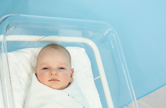 Baby Is Sleeping In Small Transparent Portable Plastic Bed. Baby Is Lying In A Hospital Crib.