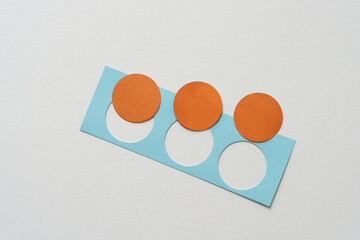 three orange discs and paper shape with circle cutouts