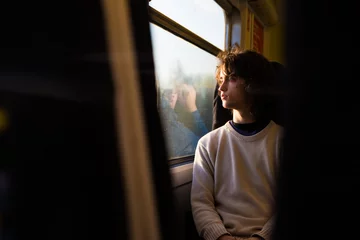 Young caucasian boy looking through a window train. © kikearnaiz
