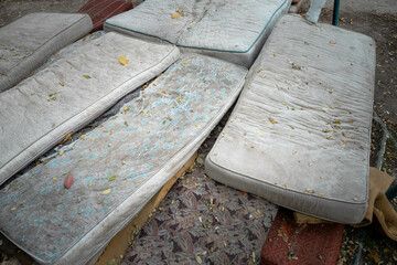 old dirty mattresses are lying on the ground. Dump of old mattresses