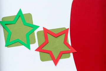 two holiday stars on green squares and a red shape on white (shadow at left)