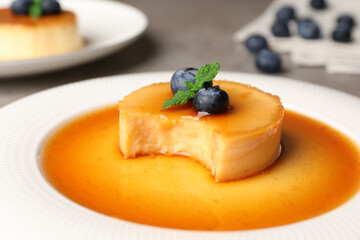 Delicious pudding with caramel and blueberries on plate, closeup