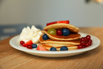 Tasty pancakes with fresh berries and whipped cream on wooden table