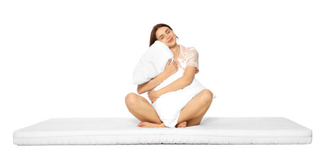Young woman on soft mattress holding pillow against white background