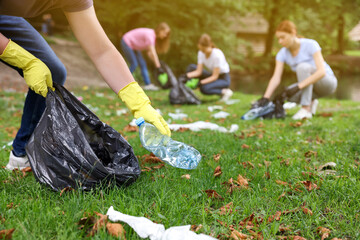 Man with plastic bag collecting garbage in park, closeup