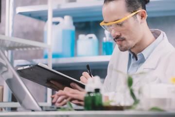 research man is standing and making notes on a pen in his notebook in a laboratory.