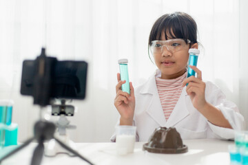 Asian school girl making easy chemistry experiments and recording a video for his followers, Young blogger kid posing in front of camera for vlog, Children make vlog for social media channel concept.