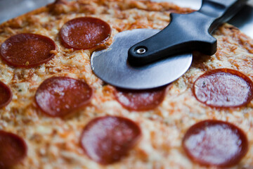 Tasty baked pepperoni and cheese thin crust pizza with pizza cutter