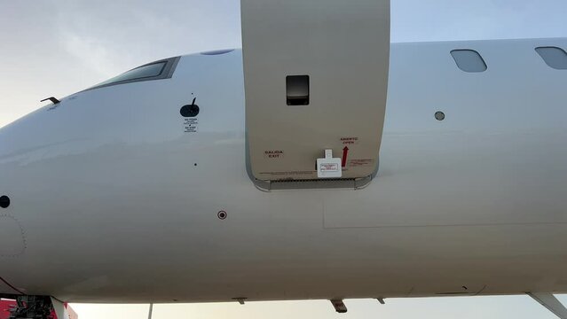 Pilot closing the door of a private jet from inside, wearing a cap and sunglasses.