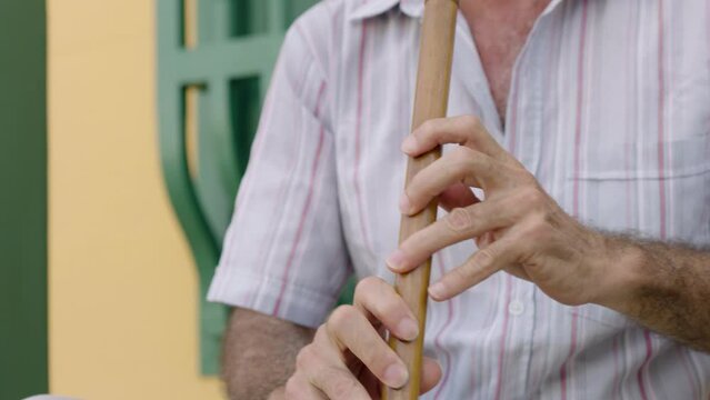 Old man playing an instrument on the front door of his house.