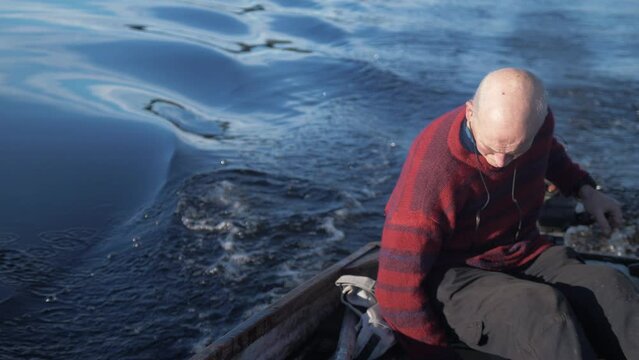 Mature man bailing rowboat while driving