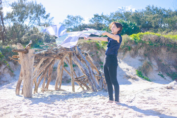 ビーチでビーチタオルを広げる女性