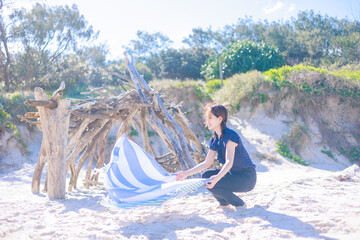 ビーチでビーチタオルを広げる女性