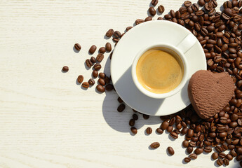 cup of coffee, roasted coffee beans,  heart-shaped cookie on a white wooden background, copy space, flat lay
