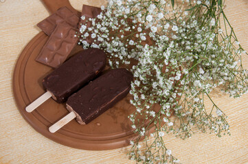 Chocolate posicle on the table with white flowers around