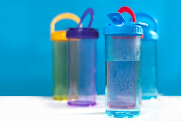 several water bottles There is a drop of water on the bottle. There are several empty water bottles in the background, blurry