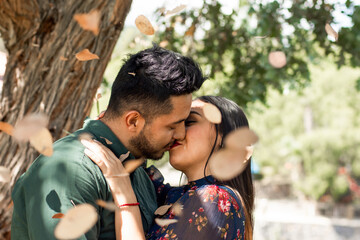 Young Hispanic couple kissing each other in a forest 