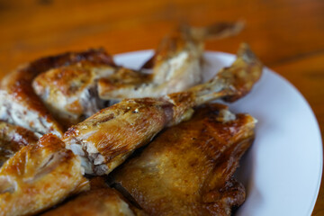 Grilled chicken in white plate on wooden floor - traditional Thai menu  It's a simple and popular dish.