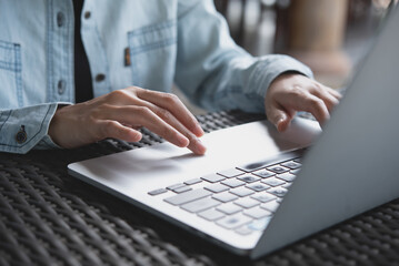 Business woman typing, working on laptop computer on table at coffee shop, connecting the internet