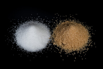 Obraz na płótnie Canvas Two piles of sugar on a black background. Comparison of white beet sugar and brown cane sugar.