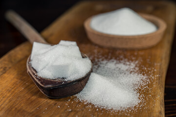Close up of white sugar cubes on a wooden spoon, on the kitchen table. Preparation of cakes and sweets in the kitchen.