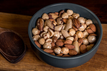 Mixture of hazelnuts, almonds and Brazil nuts, poured into a green ceramic bowl. A mix of nuts of...