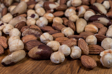Mixture of hazelnuts, almonds and Brazil nuts, scattered on a wooden board. A mix of nuts of...