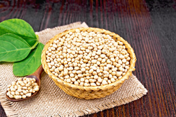Soybeans in wicker bowl with leaf on dark board